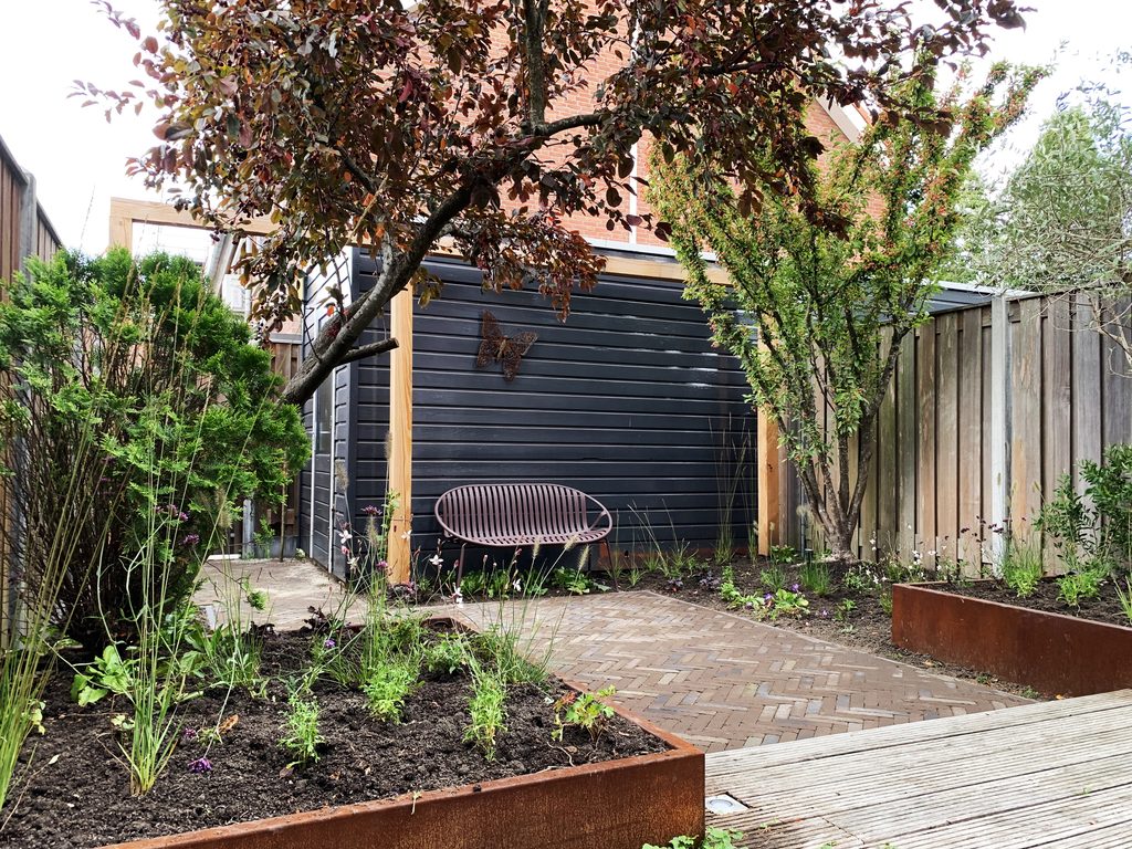 Weelderige stadstuin met gevarieerde beplanting en pergola