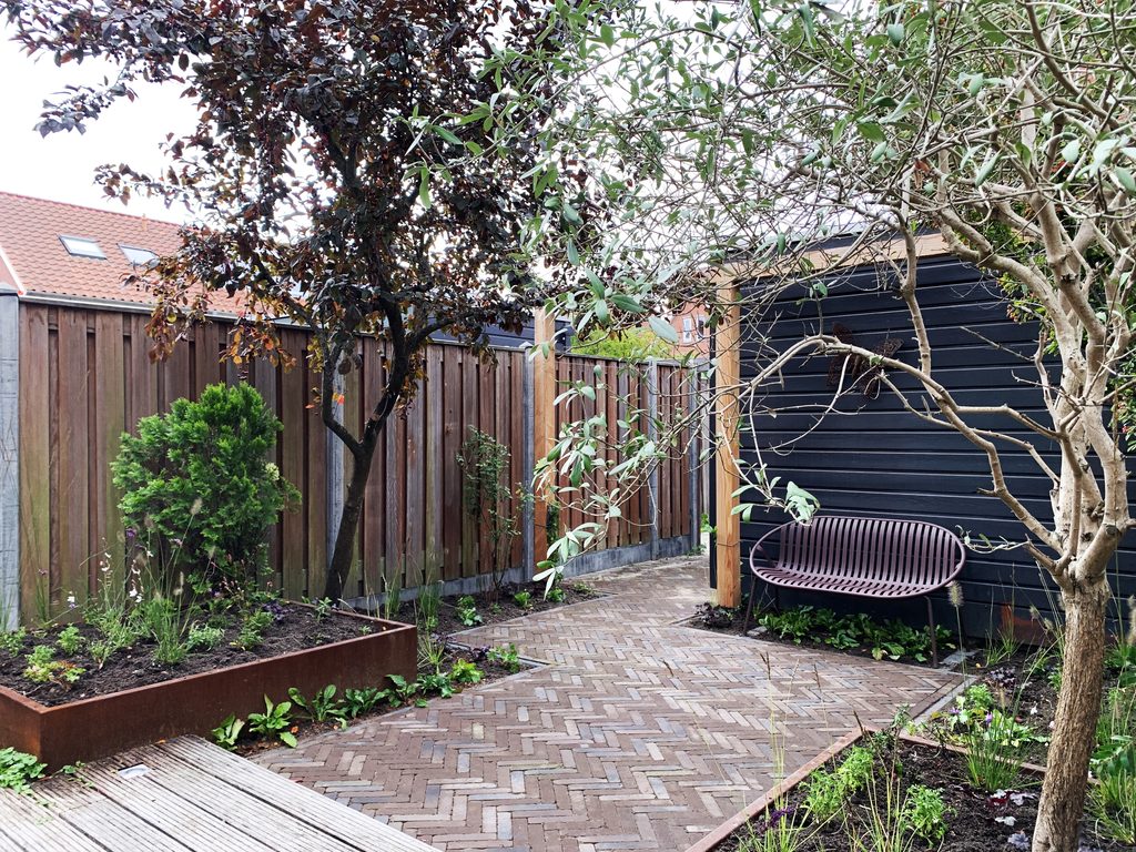 Pergola als beschutte zitplek in een groene stadstuin