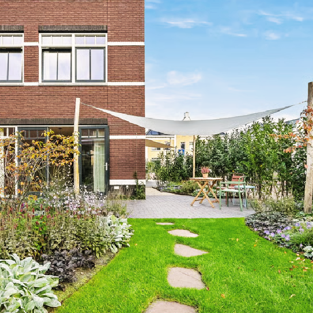 Uitzicht vanuit de achtertuin op de groene beplanting en woning in Den Haag
