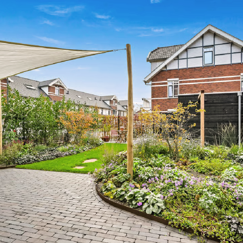 Weelderige border langs de woonkamer in een groene stadstuin in Den Haag
